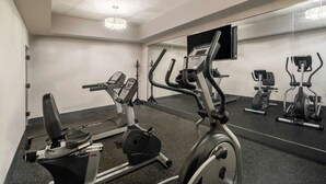 A gym with stationary bikes and a treadmill, a large mirror, and a television on the wall. - Baymont by Wyndham Franklin/Cool Springs (Franklin)