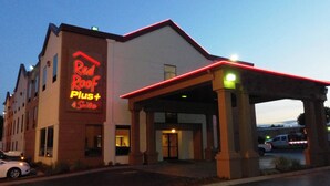 A hotel with a prominent 'Red Roof Plus' sign, a covered entrance, and a parking lot.