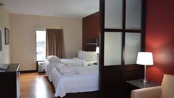 A hotel room with two beds, a desk, a chair, and a window with curtains.