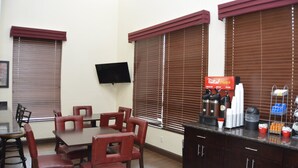 Une salle de conférence équipée d’une table et de chaises, d’un téléviseur fixé au mur et d’un coin café avec divers articles.