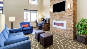 A spacious lobby with a stone accent wall, a flat-screen TV, comfortable seating, and a large window. - Comfort Inn at Royal Blue (Pioneer)
