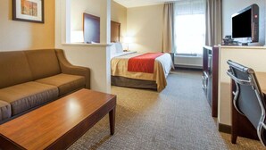 A hotel room with a sofa, a bed with a red blanket, a desk with a flat-screen TV, and a window with curtains. - Comfort Inn at Royal Blue (Pioneer)