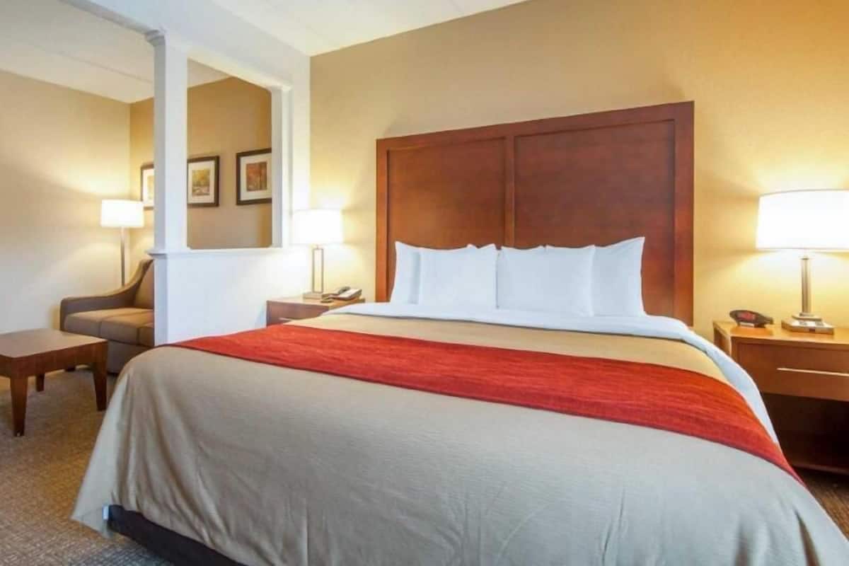 A hotel room with a large bed, two bedside tables with lamps, a chair, and a mirror.
