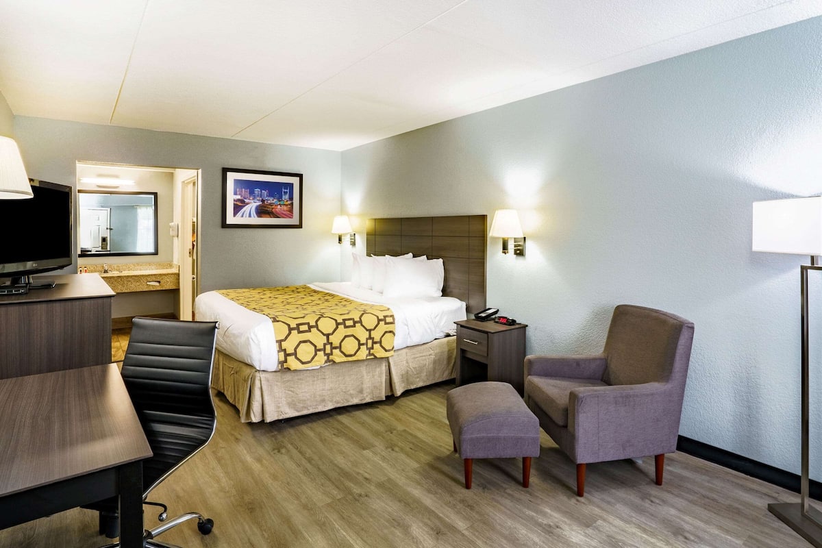 Een hotelkamer met een bed, een bureau, een stoel, een televisie en een nachtkastje.