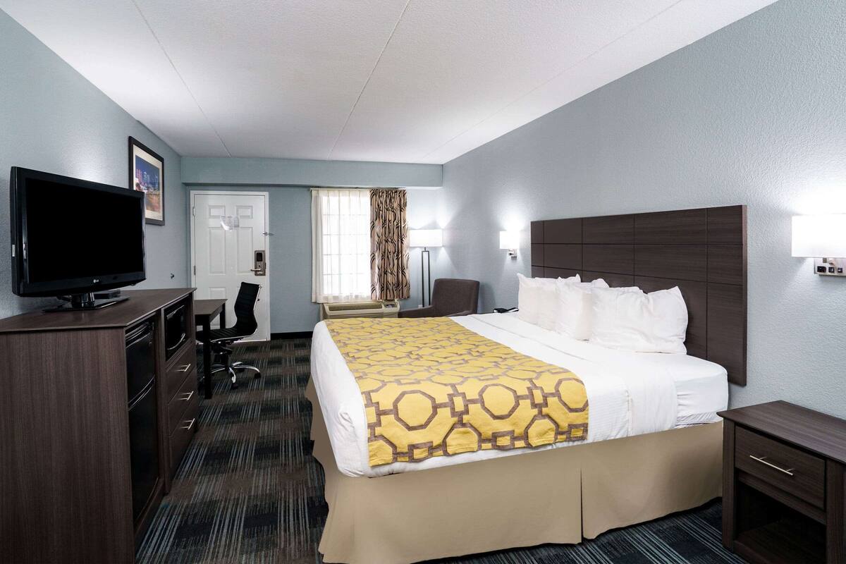 Een hotelkamer met een bed, een bureau, een televisie en een stoel.