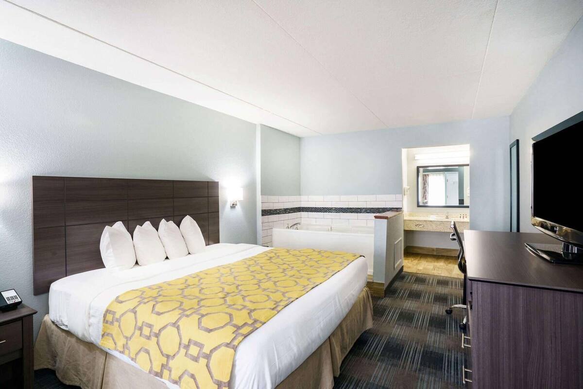 Hotelkamer met een groot bed, een aparte badkamer, een bureau met een televisie en een klein raam.