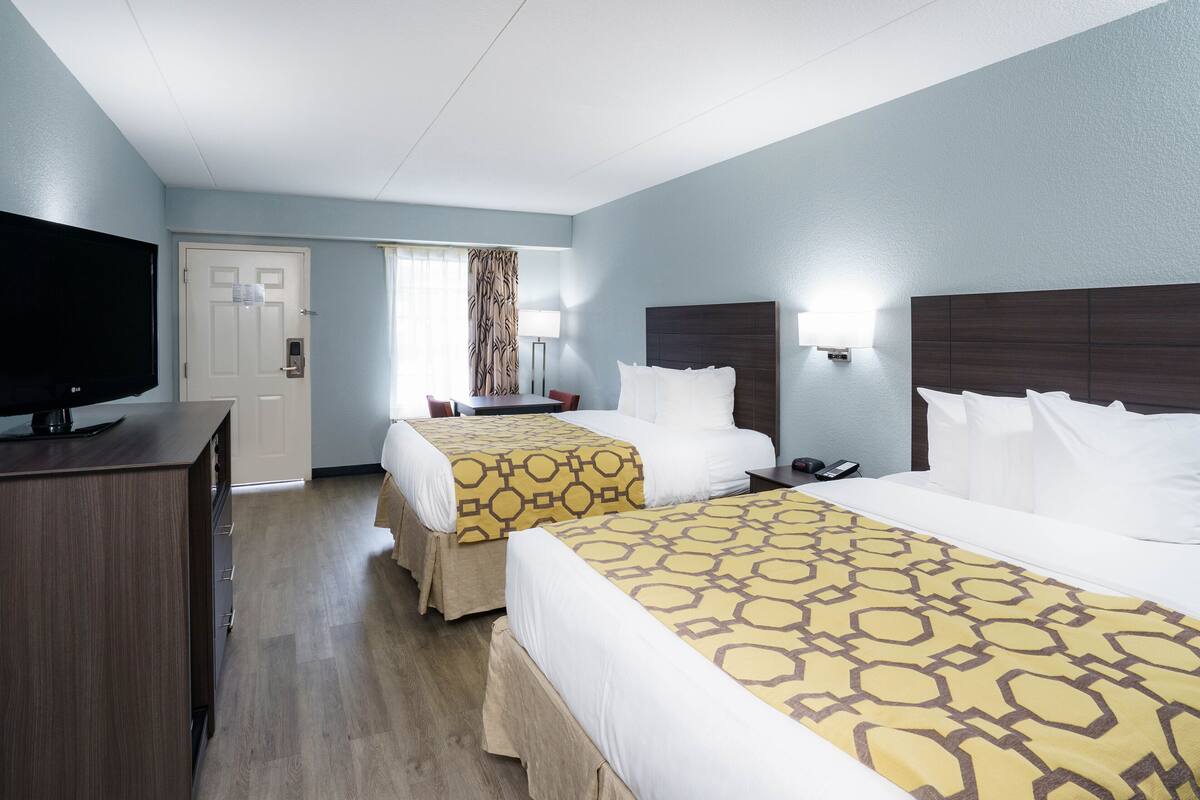 Een hotelkamer met twee bedden, een televisie, een bureau en een raam met gordijnen.