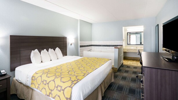Hotelkamer met een bed, bureau, televisie, badkamer met bad en een raam.