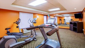 Een hotelfitnessruimte met loopbanden, hometrainers en een spiegelwand.