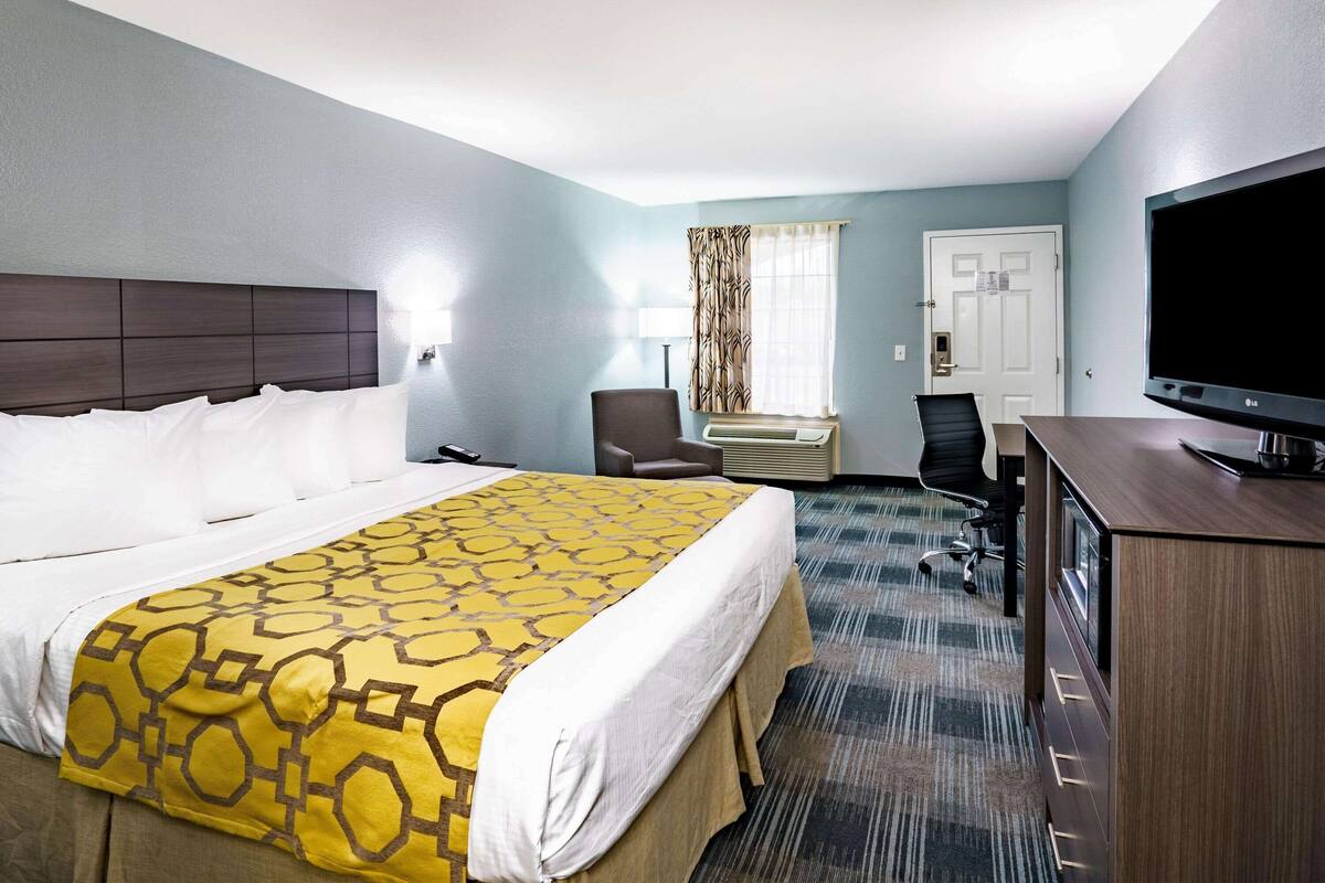 Een hotelkamer met een groot bed, een bureau, een stoel en een televisie.
