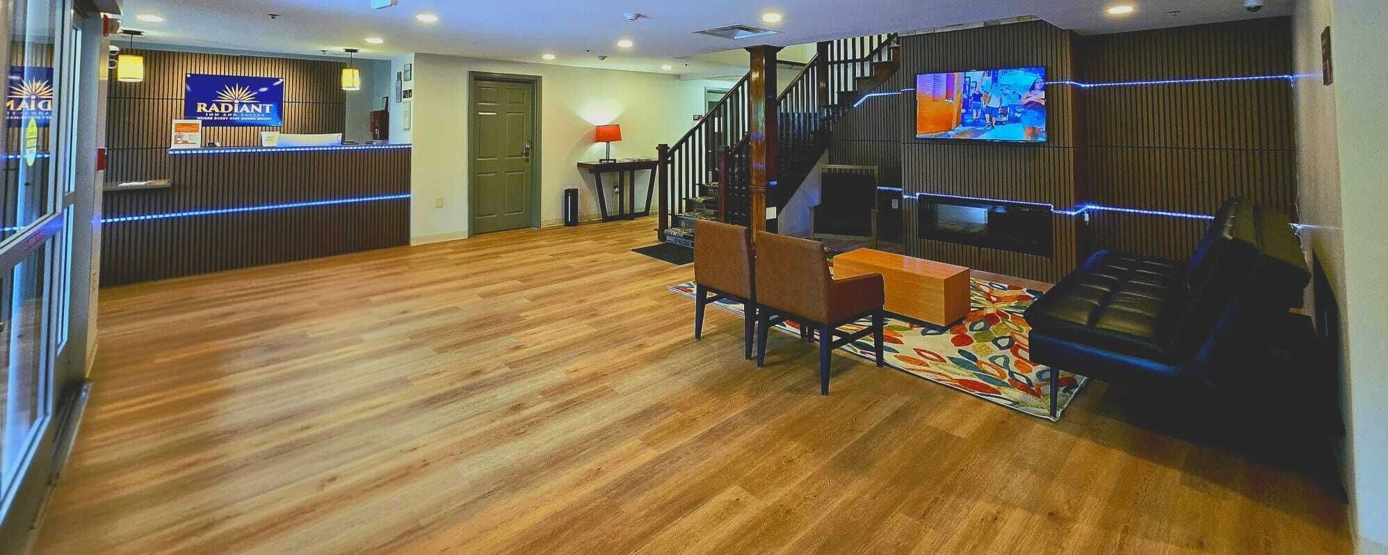 Un vestíbulo de hotel con mostrador de recepción, una escalera y un área de estar con una mesa de centro y sillas.