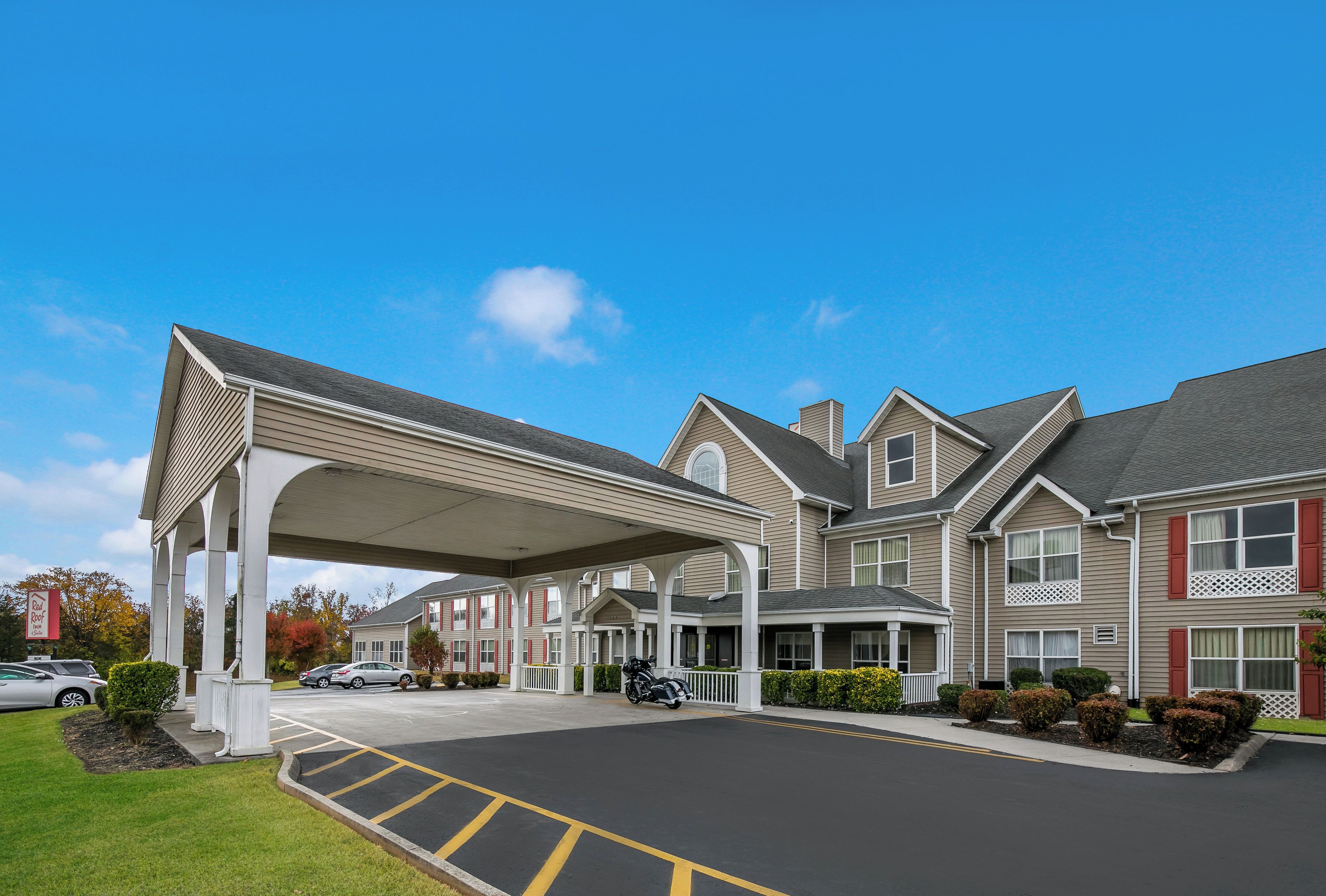 A large hotel with a covered entrance, multiple windows, and a parking lot.