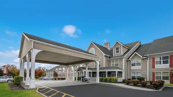 A large hotel with a covered entrance, multiple windows, and a parking lot.