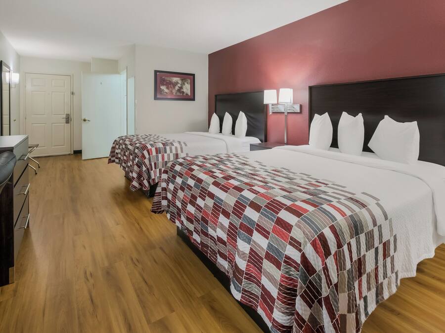 Ett hotellrum med två sängar, ett skrivbord och en dörr.