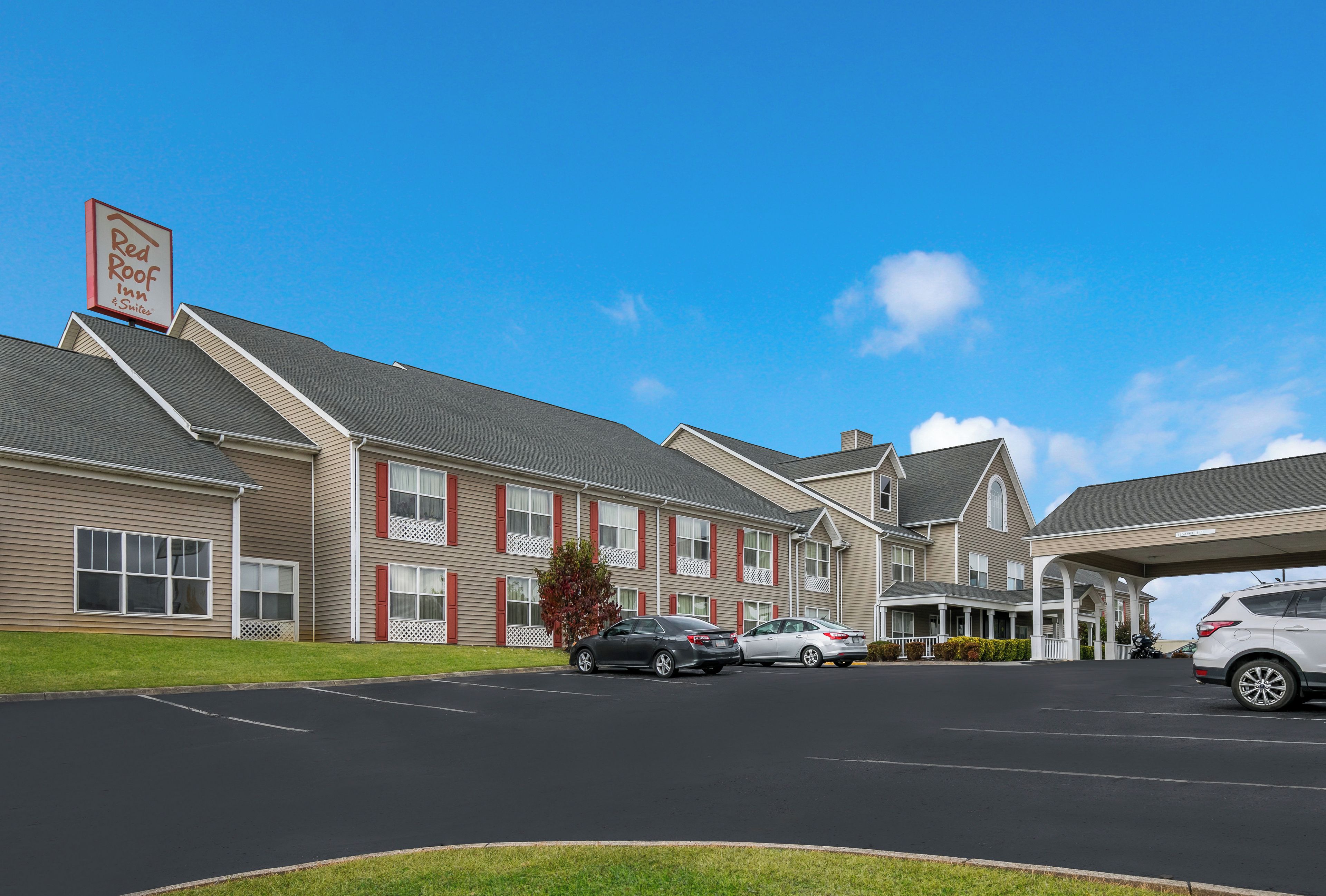 A Red Roof Inn with a parking lot and multiple vehicles.