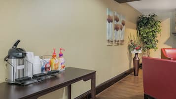 A reception area with a coffee station, a red chair, and a potted plant.
