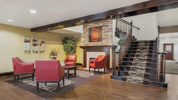 A hotel lobby with a fireplace, red leather chairs, a staircase, and a Red Roof Inn sign.