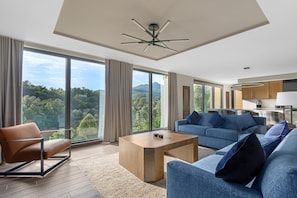 A modern living room with a large window, a sofa, a coffee table, and a ceiling fan. - Hilton Vacation Club MountainLoft Gatlinburg (Gatlinburg)