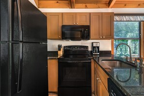 Una cocina con un refrigerador negro, un microondas, una estufa y un lavaplatos.