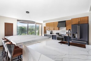 Una cocina moderna con una isla grande, taburetes de bar y vistas al exterior.