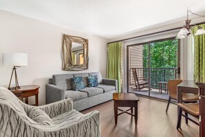 A modern living room with a grey sofa, patterned armchair, and a dining area with a table and chairs. - Hilton Vacation Club MountainLoft Gatlinburg (Gatlinburg)