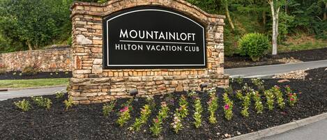Un letrero de piedra con la inscripción 'MOUNTAINLOFT' y 'HILTON VACATION CLUB'.