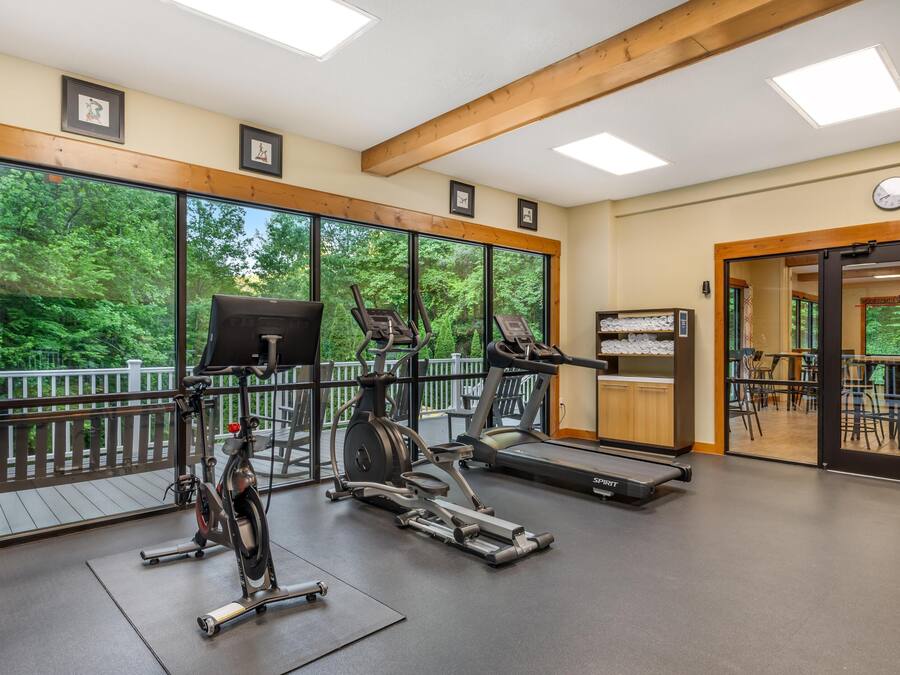 Un gimnasio con bicicletas estáticas, cintas de correr y un banco de pesas.