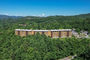 A multi-story hotel with a flat roof, surrounded by dense forest, and a clear sky. - Hilton Vacation Club MountainLoft Gatlinburg (Gatlinburg)