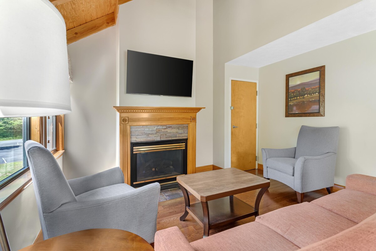 A living room with a fireplace, a television mounted on the wall, and a painting.