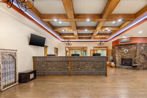A reception area with a stone fireplace, wooden ceiling beams, and a flat-screen TV mounted on the wall. - Hilton Vacation Club MountainLoft Gatlinburg (Gatlinburg)