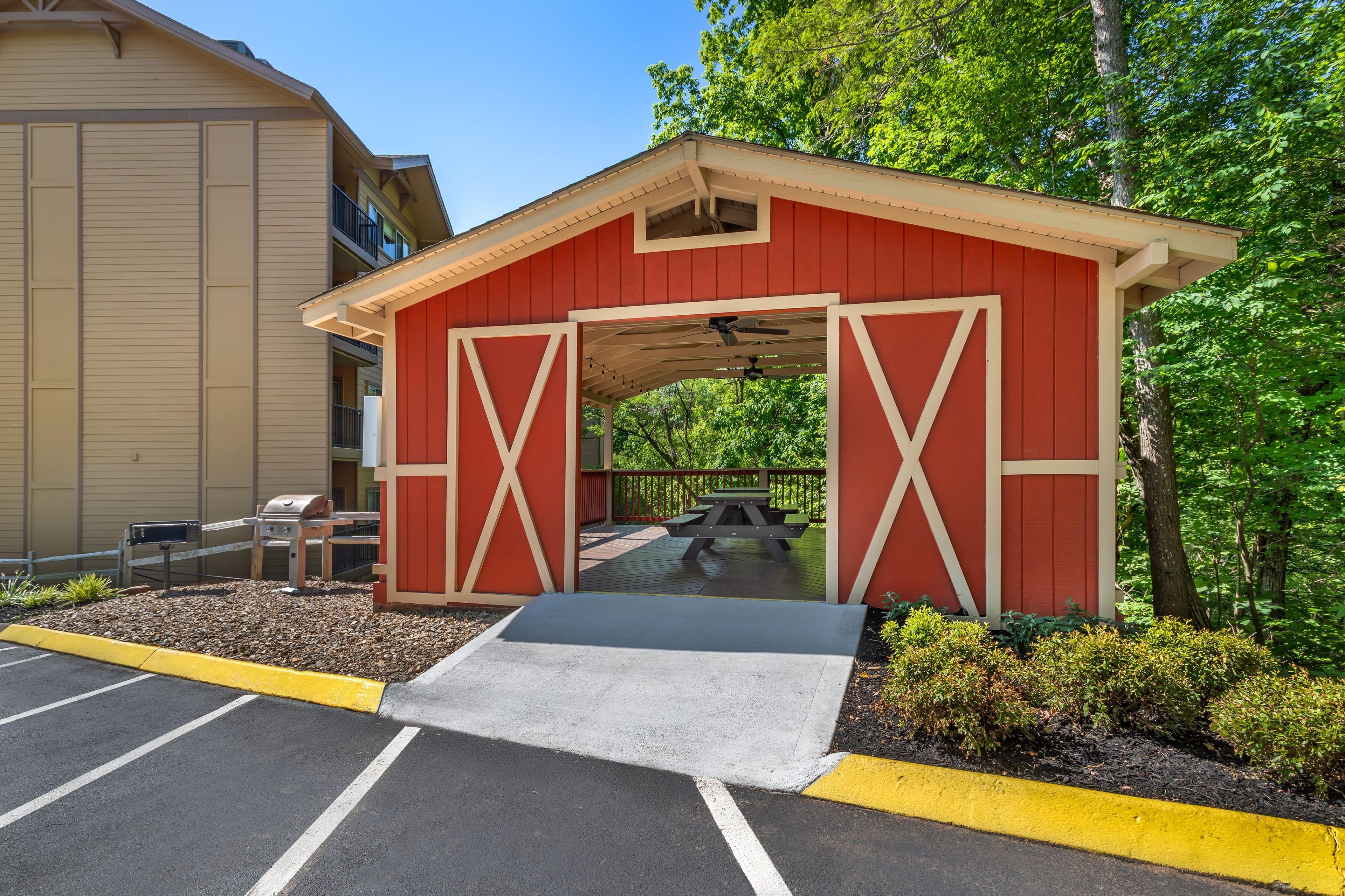 A red building with a covered entrance and a ramp leading to a picnic table.