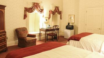 A hotel room with two beds, a desk with a chair, a dresser, and a microwave.