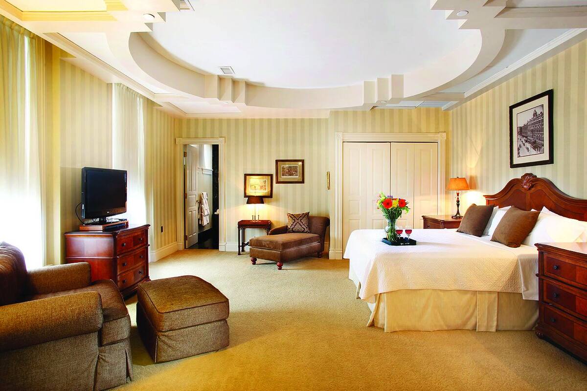 A hotel room with a bed, a television, a desk, a chair, and a lamp.
