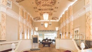 A grand hallway with a marble floor, a red carpeted staircase, and a chandelier. - General Morgan Inn (Greeneville)