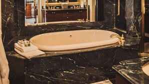 A luxurious bathroom with a large marble sink, a freestanding bathtub, and a mirror above the sink.