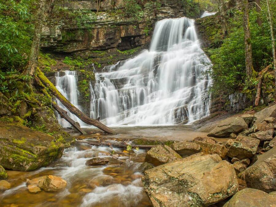 Ein Wasserfall stürzt über Felsen in einem bewaldeten Gebiet.