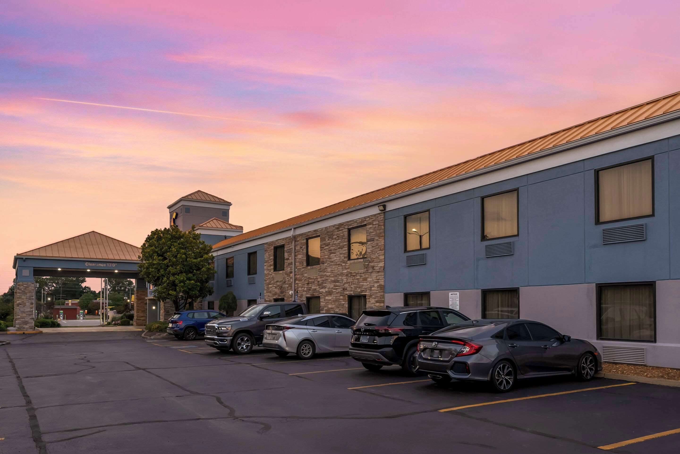 A hotel with a parking lot and several cars parked.