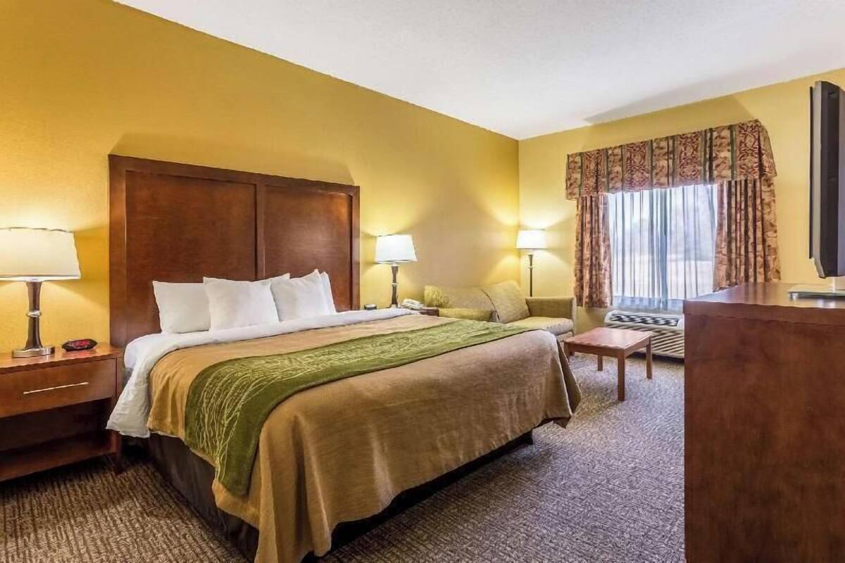 A hotel room with a large bed, two bedside tables with lamps, a desk, and a television.