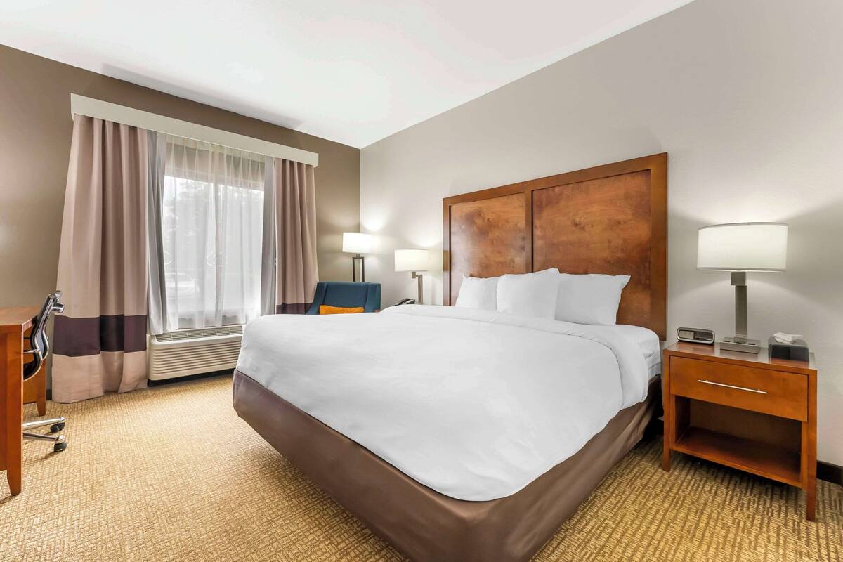 A hotel room with a large bed, two bedside tables with lamps, a desk, and a chair.