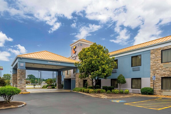 A hotel with a clear 13' entrance, a stone facade, and a parking lot.