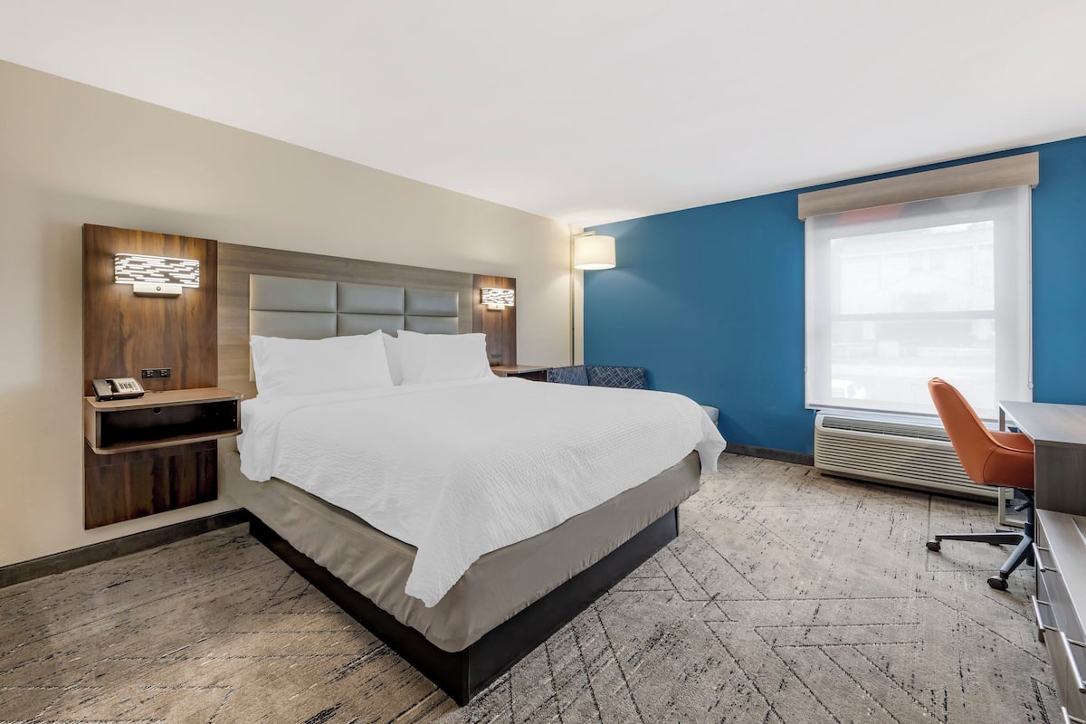 Une chambre d’hôtel avec un lit, un bureau et une chaise.