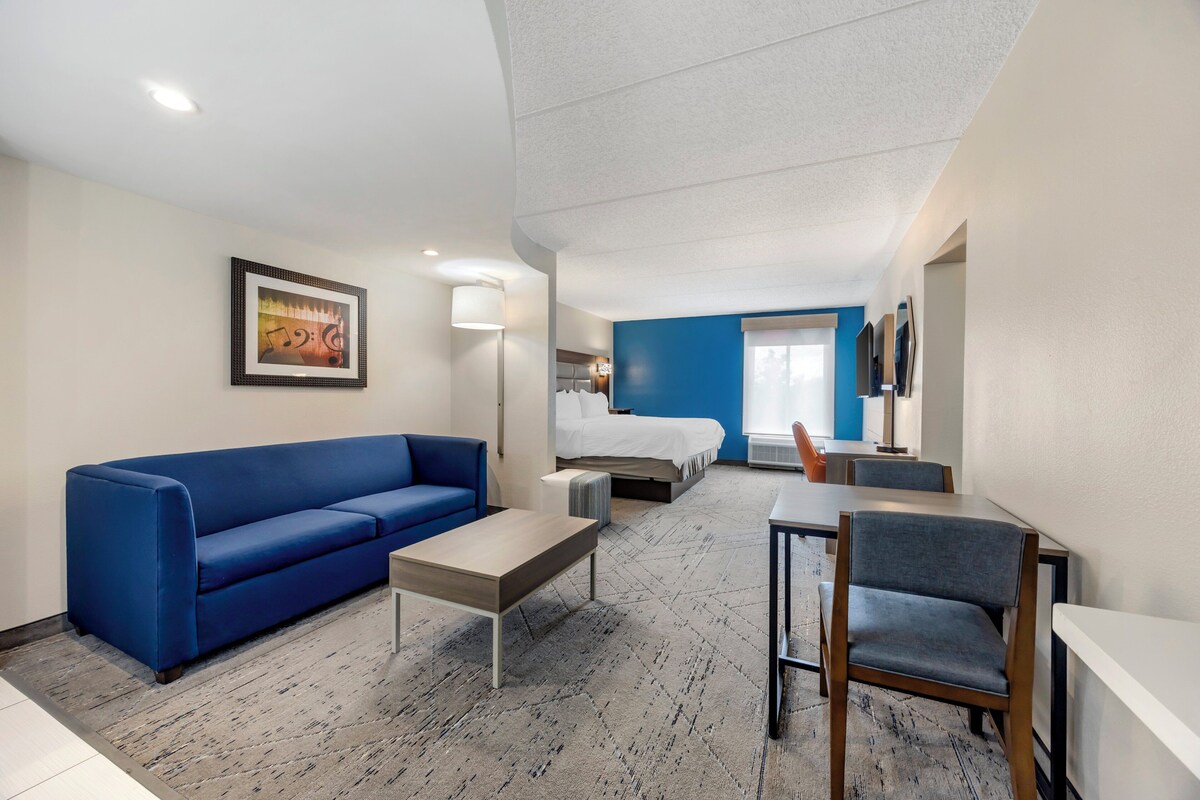 Une chambre d’hôtel moderne avec un canapé bleu, un lit, une petite table et une chaise.
