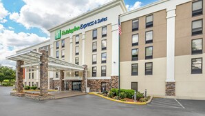 Een Holiday Inn Express & Suites gebouw met een overdekte entree, stenen pilaren en een vlag.