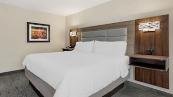 Una habitación de hotel moderna con una cama grande, una mesita de noche, un estante en la pared y un cuadro enmarcado.