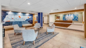 Een moderne lobby met een receptiebalie, een zithoek en een groot muurdecor.