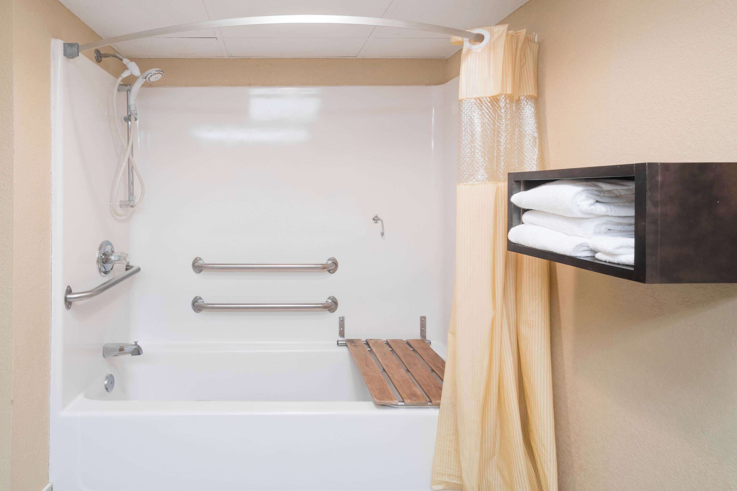 Un baño con bañera, ducha y un estante con toallas.