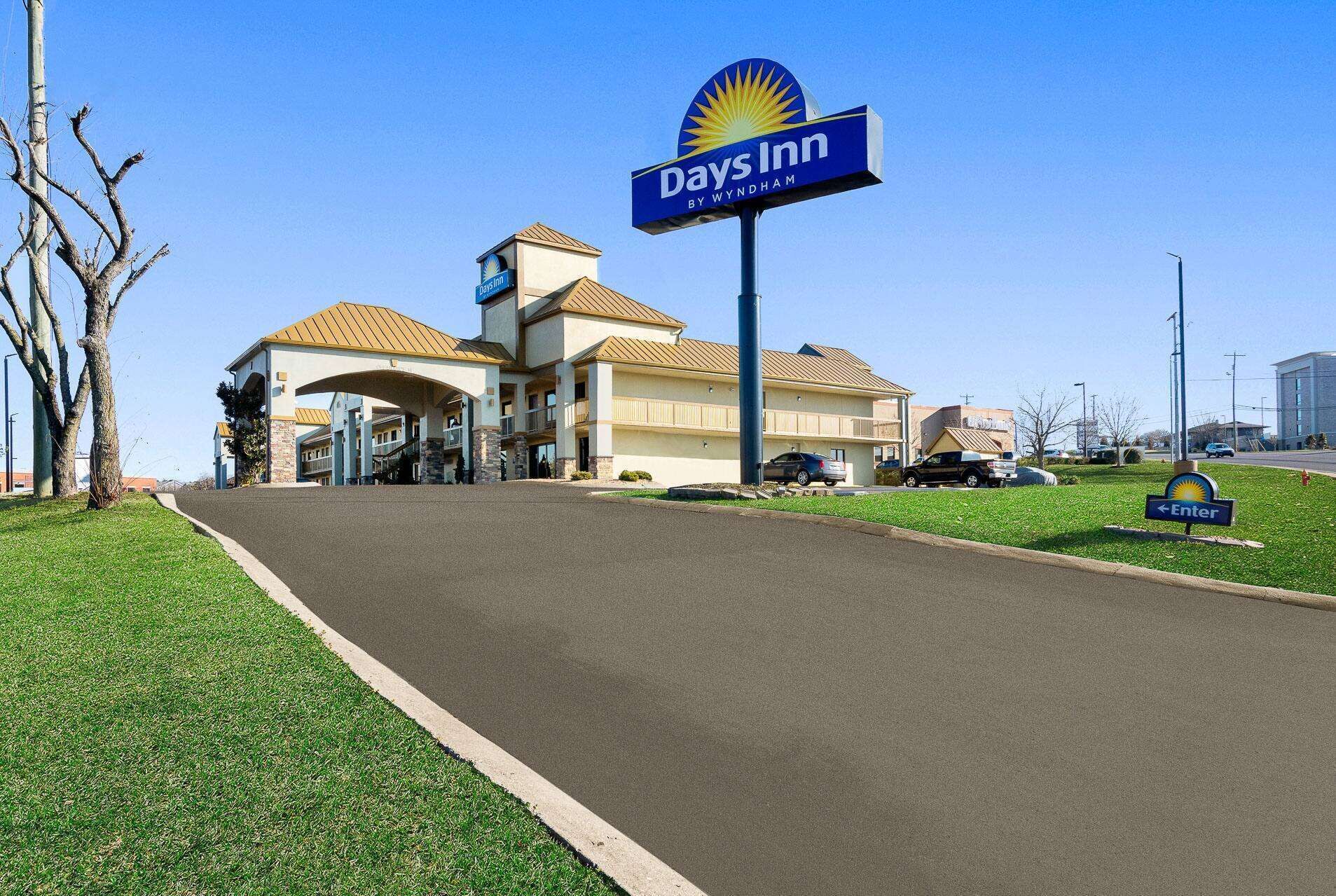 Un hotel Days Inn by Wyndham con un grande cartello, un parcheggio e cielo sereno.