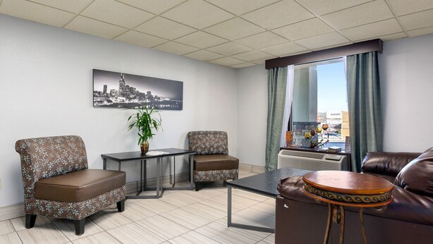 A hotel room with a cityscape view, two patterned armchairs, a small table, a leather sofa, and a decorative drum. - Days Inn by Wyndham Goodlettsville/Nashville (Goodlettsville)