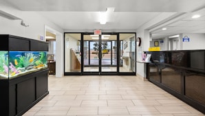 A lobby with a fish tank, a reception desk, and an exit sign. - Days Inn by Wyndham Goodlettsville/Nashville (Goodlettsville)