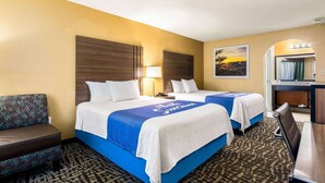 A hotel room with two beds, a sofa, a desk, and a bathroom mirror. - Days Inn by Wyndham Goodlettsville/Nashville (Goodlettsville)